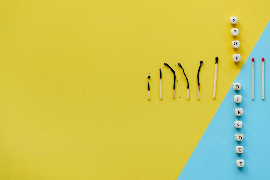 A line of matches, with some burned and others unburned, separated by a barrier, symbolizing the act of protecting oneself from burnout.